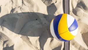 Piłka do siatkówki leżąca na piasku.